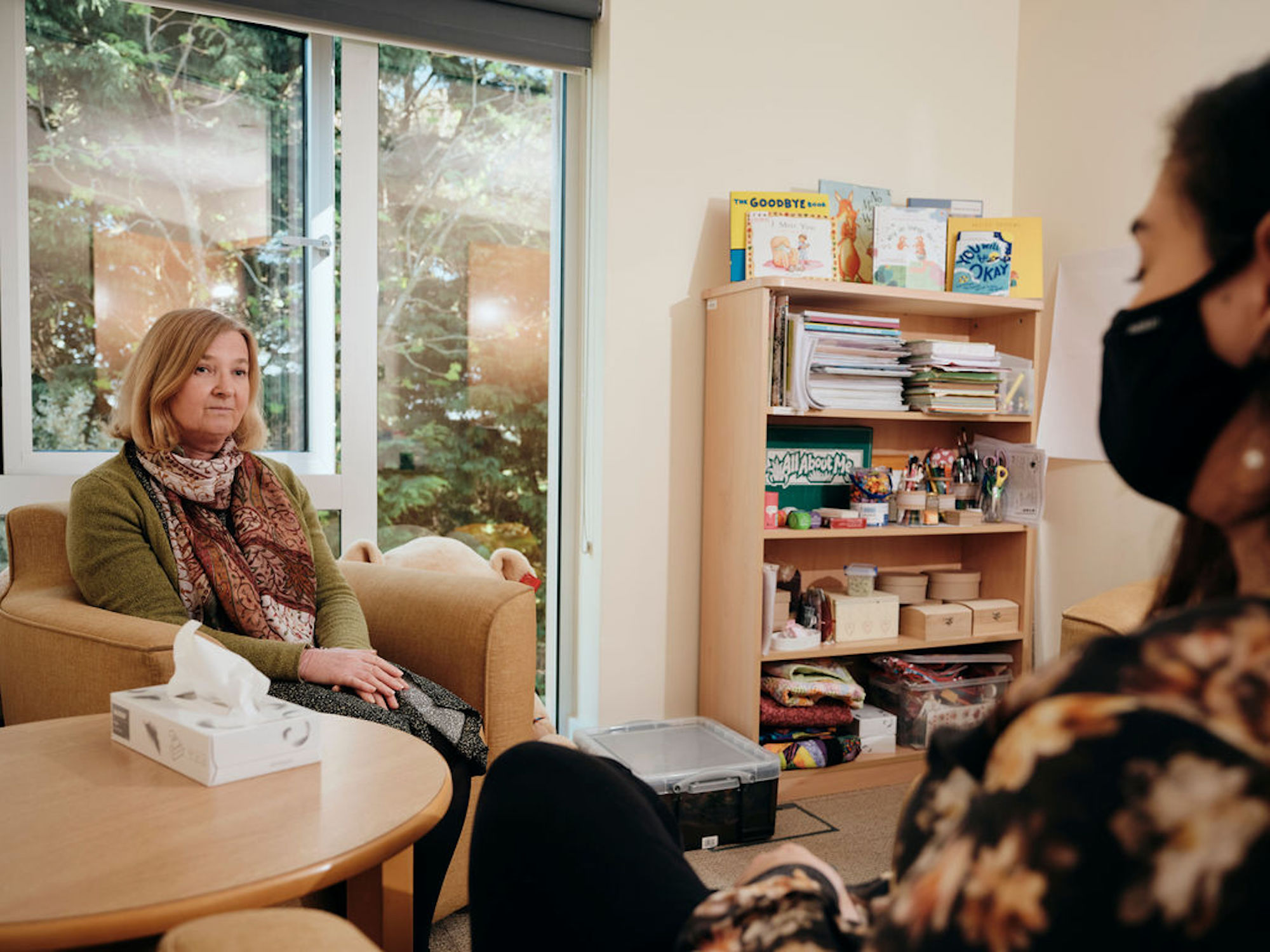 Image of bereavement counsellor talking to patient, box of tissues on table 