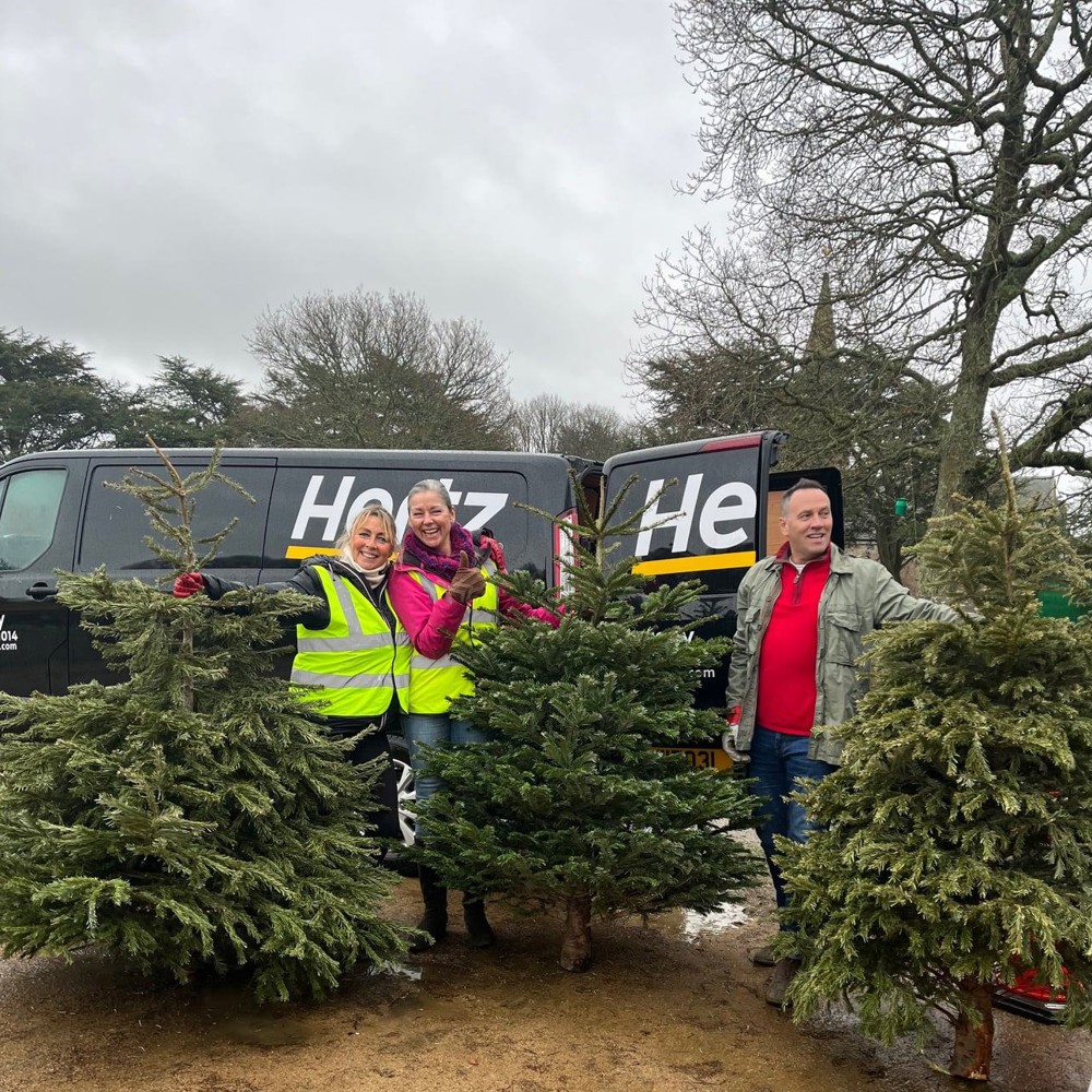 Image of three people with Christmas Trees