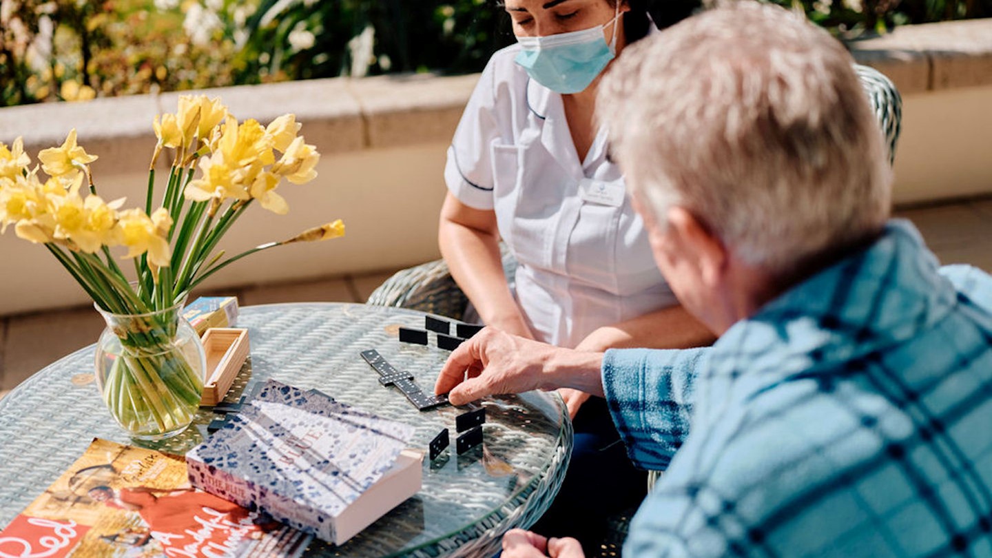 Image of nurse and patient playing dominos 