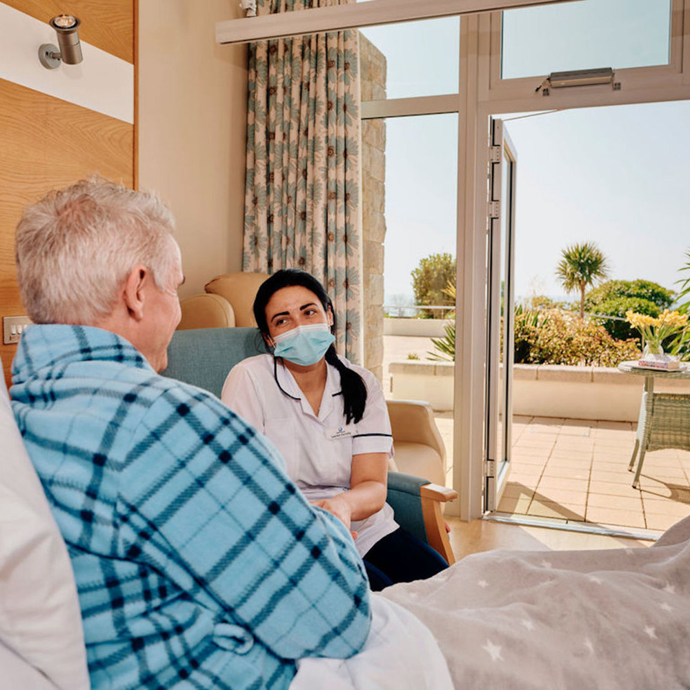 Image of nurse next to patients bed