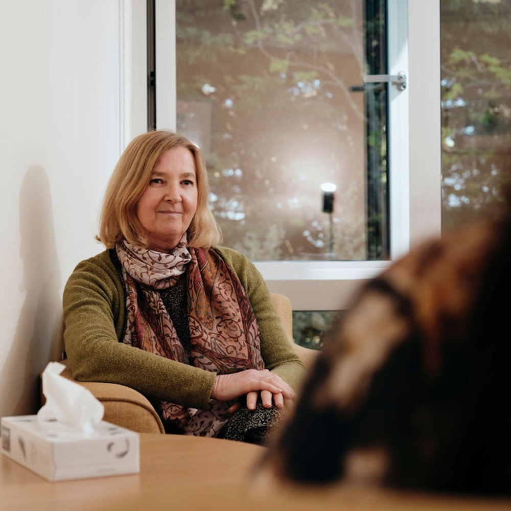 Image of bereavement counsellor talking to patient, box of tissues on table 