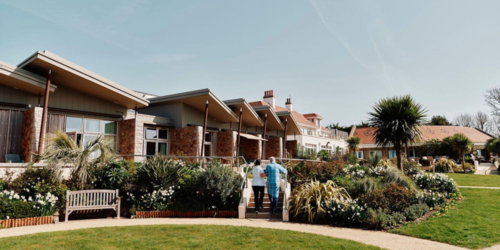 Image of nurse and patient walking up stairs in Hospice gardens with Hospice building behind them