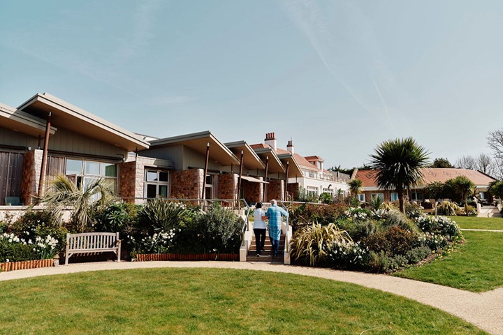 Image of nurse and patient walking up stairs in Hospice gardens with Hospice building behind them