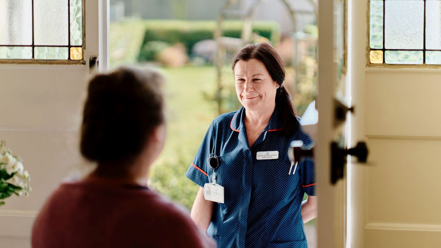 Image of community nurse at doorway visiting patient 