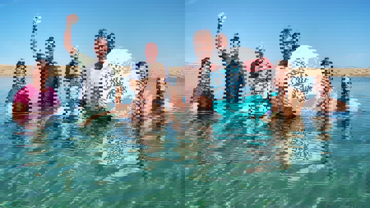 Image of swimmers in the sea with 30 Bays in 30 Days sign
