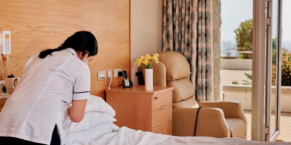 Image of nurse making a bed in patient room