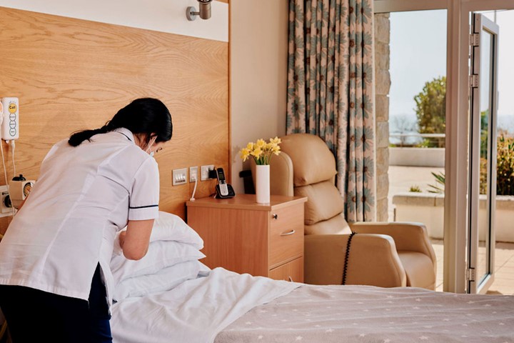 Image of nurse making a bed in patient room