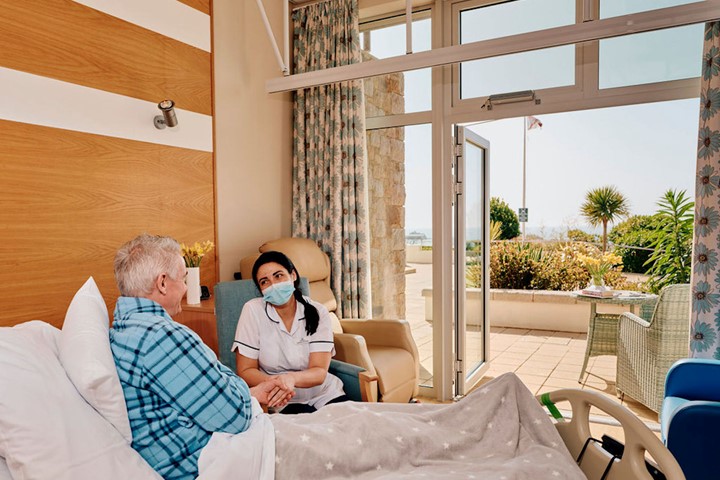 Image of nurse holding hands with a patient in In Patient Unit at Hospice