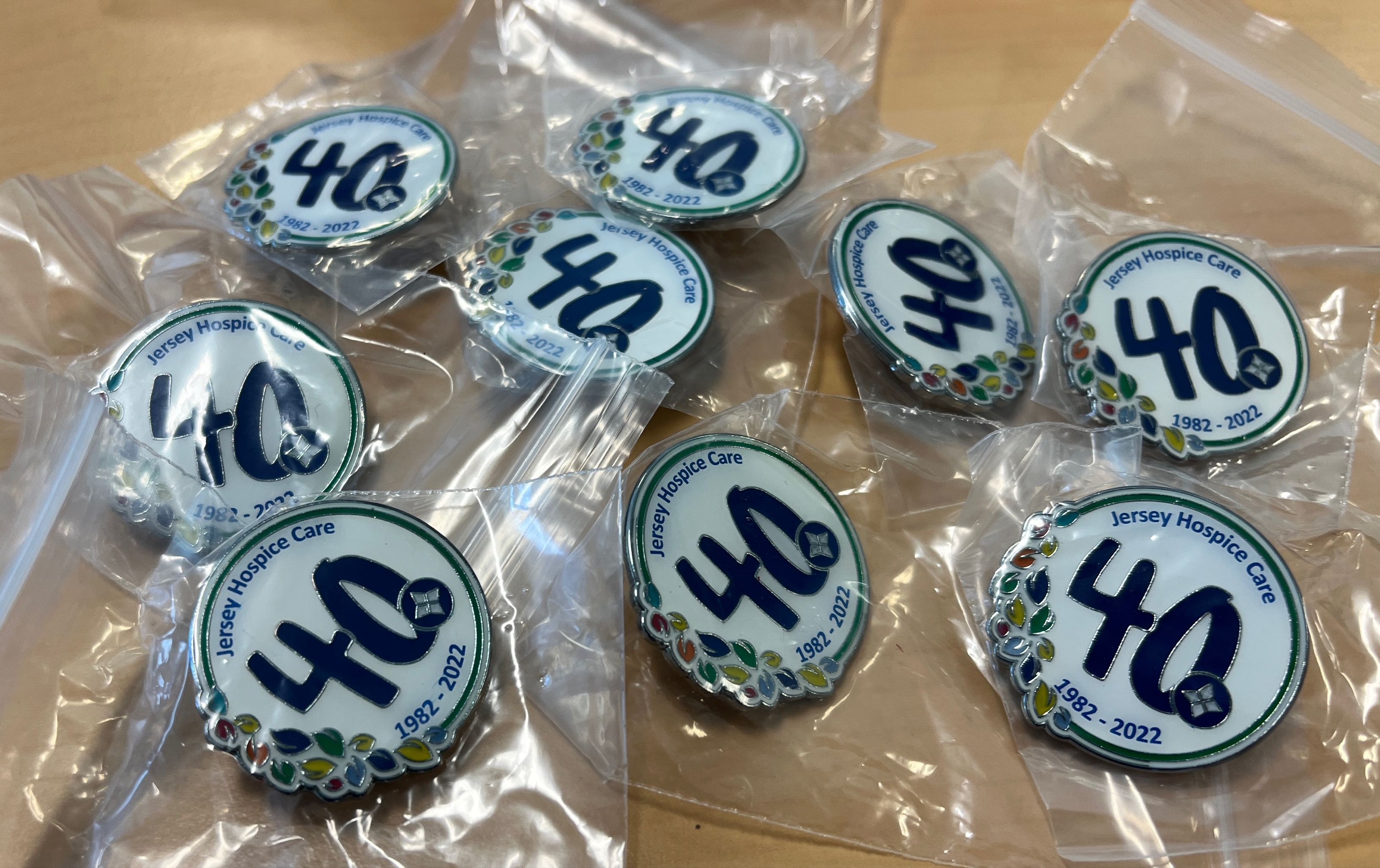 Selection of pin badges branded with Jersey Hospice Care 40th logo