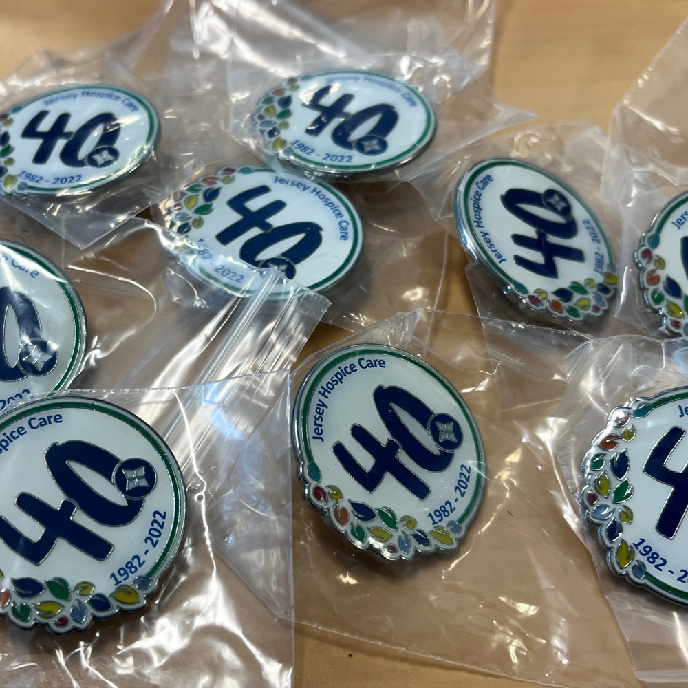 Selection of pin badges branded with Jersey Hospice Care 40th logo