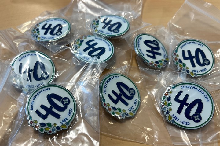 Selection of pin badges branded with Jersey Hospice Care 40th logo