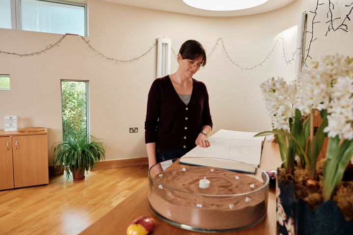 Image of Rev Emily in the sanctuary looking at memory book, flowers and candles