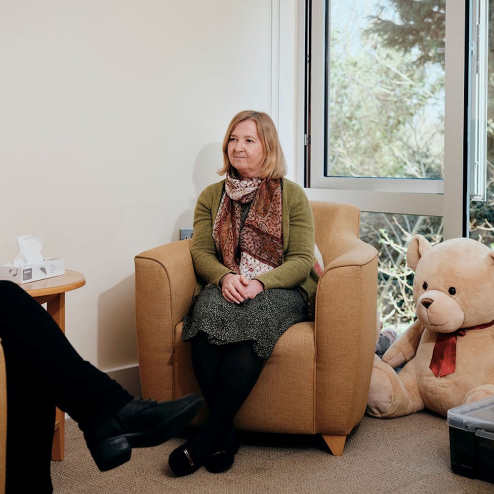 Image of bereavement counsellor talking to patient, box of tissues on table 